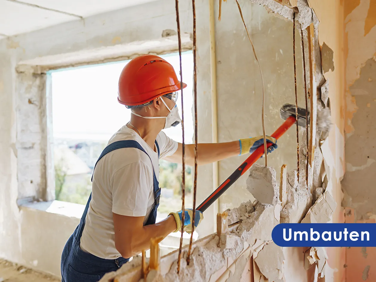 Umbau: Arbeiter bricht eine Wand mit dem Vorschlaghammer auf