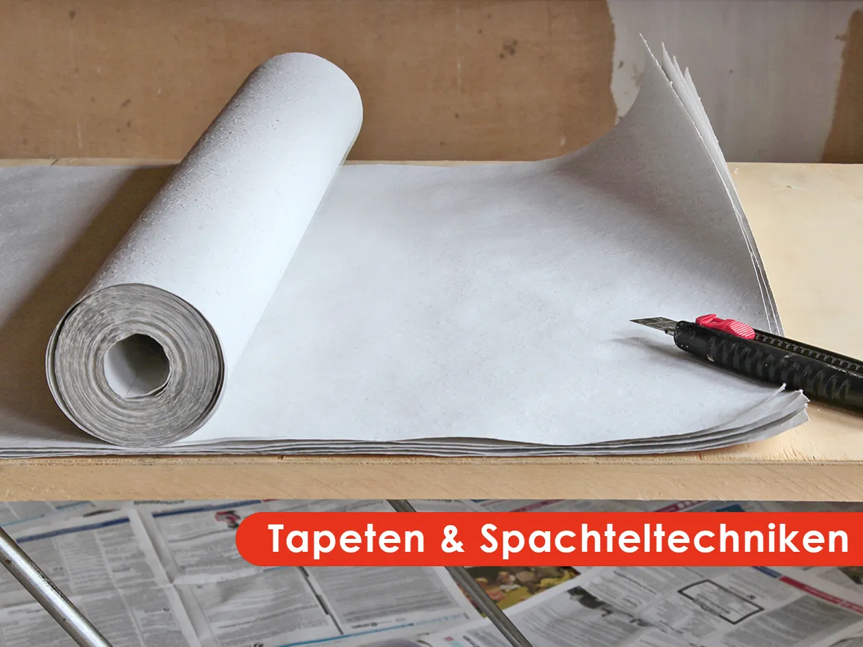 Tapetenrolle und Cuttermesser auf dem Tapeziertisch